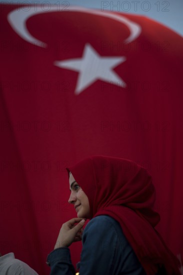 Istanbul, Turkey, July 17th 2016 Turkish Muslim Woman with red headscarf with Turkish flag behind