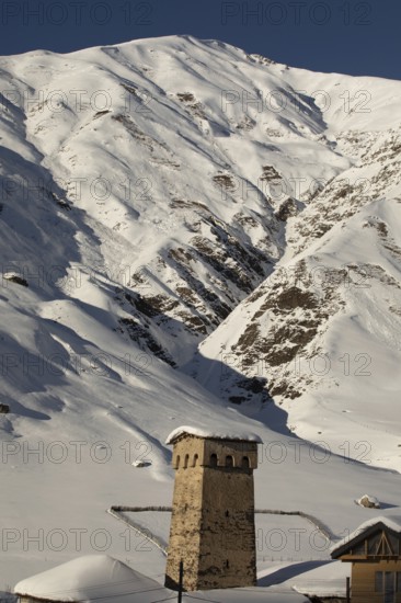 A stone tower stands amid a stunning snowy mountain landscape in Georgia The scene highlights the