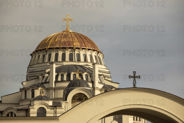 The image showcases a stunning golden dome of an orthodox church against a cloudy sky in Georgia