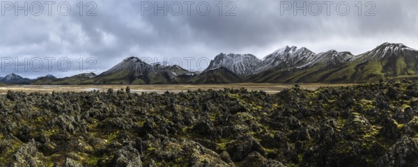 A breathtaking panoramic view of Iceland's rugged Highlands, showcasing jagged peaks, moss-covered