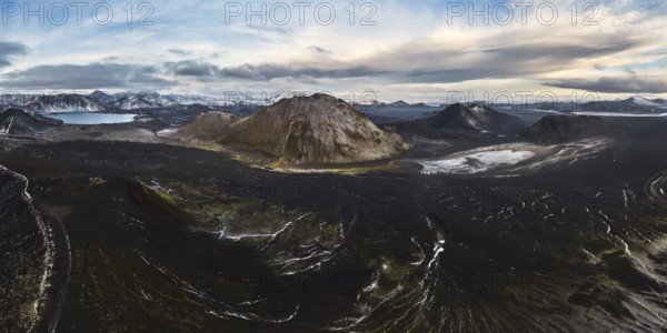 A breathtaking view of a volcanic mountain surrounded by lush green moss, winding rivers, and