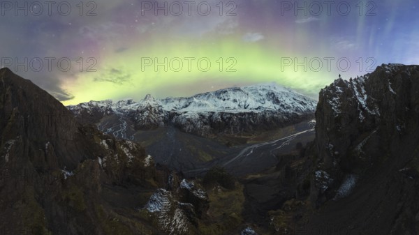 Breathtaking view of the Northern Lights illuminating the sky above a snow-covered mountain range