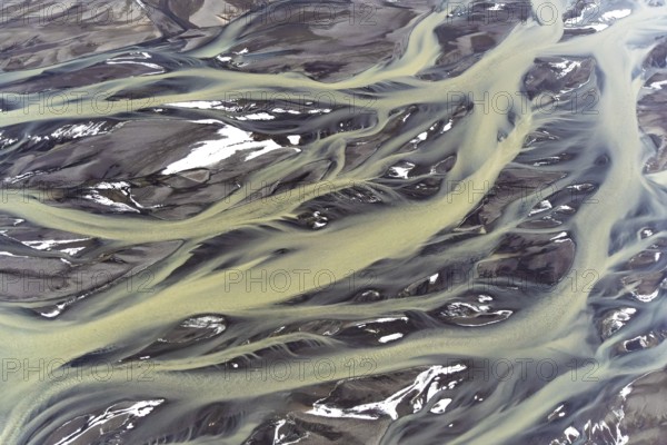 Stunning aerial capture of Iceland's golden rivers, gracefully weaving through patches of snow,