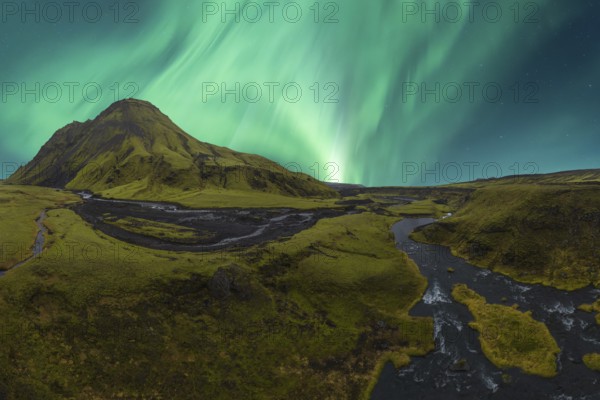 Majestic Northern Lights dance in the sky above a vibrant green valley in Iceland, with a
