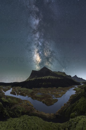 Breathtaking night sky over Iceland, capturing the Milky Way above a serene river and rugged