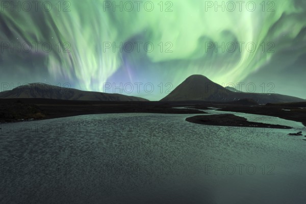 Majestic Northern Lights (Aurora Borealis) illuminate the night sky above a serene Icelandic lake,