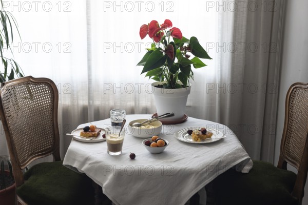 Warmly lit coffee table covered in a white cloth, featuring various desserts like cherry-topped