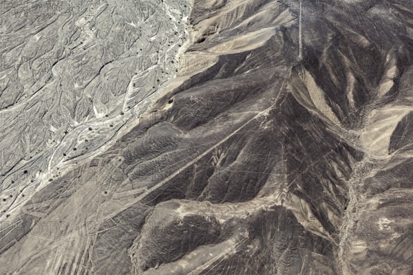 Aerial photo shows hills with extensive line patterns in an arid region, the geoglyphs and images