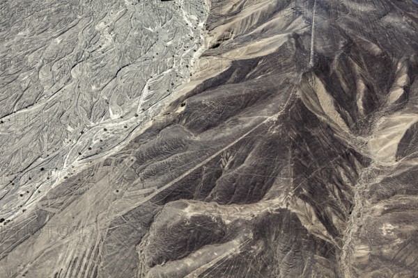 Aerial view of a desert with distinctive hills and line patterns, the geoglyphs and images in the