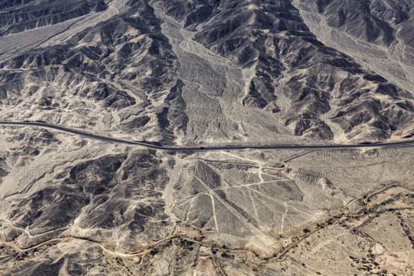 Barren landscape with visible geoglyphs and a straight road, the geoglyphs and images in the desert