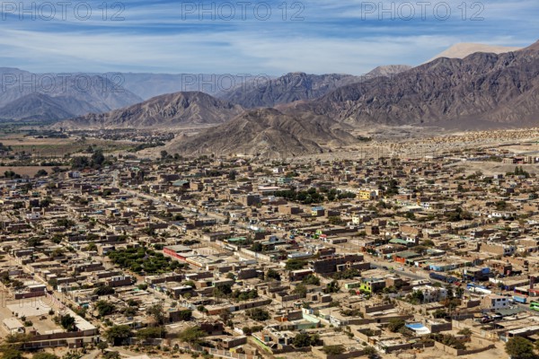 A panoramic view of a city against a backdrop of mountains and clear skies, the city of Nasca in