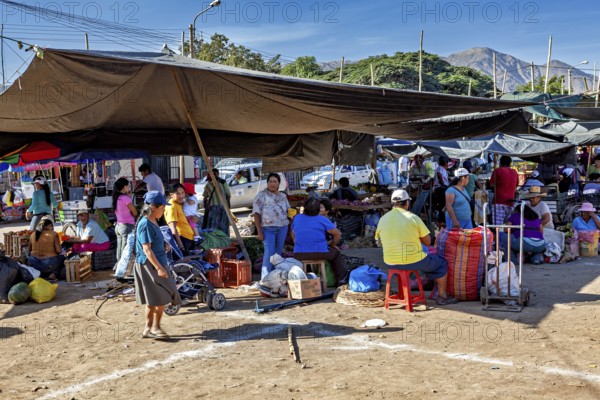 A bustling market against a mountain backdrop with lots of stalls and people, The market in the