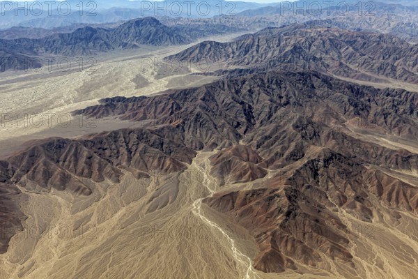 Winding hills and a dry riverbed in an impressive, dry landscape with shades of brown colors, The