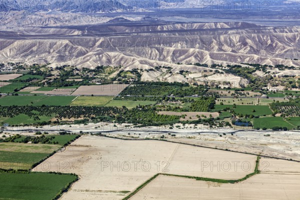 Extensive green areas and riverbed with mountain ranges on the horizon, the desert landscape near