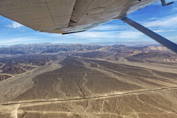 View from an airplane of a dry desert landscape with mountains and blue sky, The desert landscape