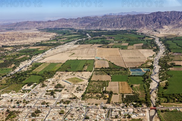 View of fields and cityscape along a river and mountains in the background, The desert landscape