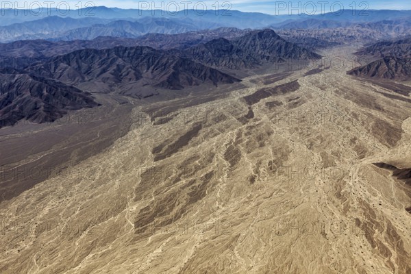 Large-scale desert landscape with a complex pattern of dry river beds surrounded by a mountain
