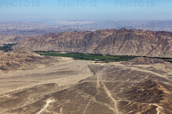 Dramatic desert plain with tracks and mountain panorama under clear sky, the desert landscape near