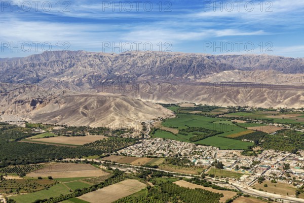 Diverse landscape with green fields and cityscape in front of a mountain panorama, The desert