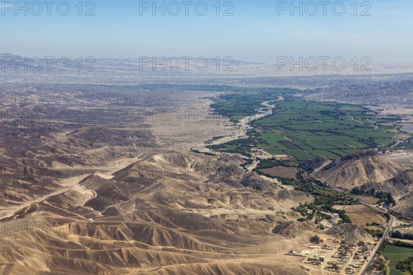 Wide desert-like landscape with a narrow green river valley in the foreground, the desert landscape