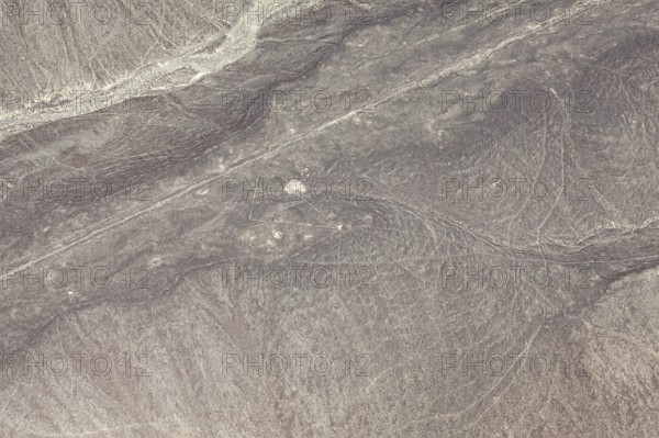 Aerial view of line patterns in a dry, sandy desert landscape, the geoglyphs and images in the