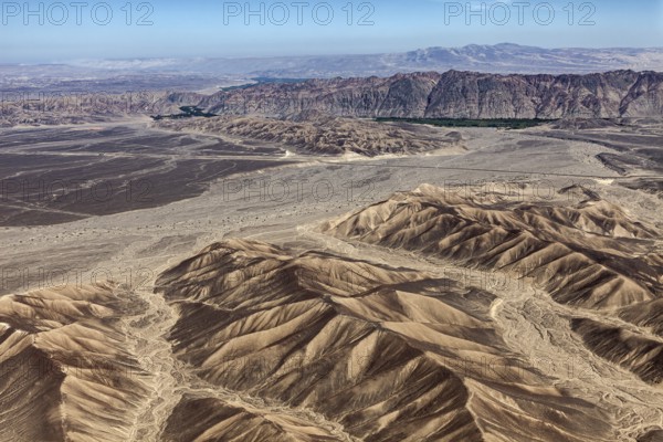 Wide desert landscape with sandy mountains and clear skies that accentuate aridity and vastness,