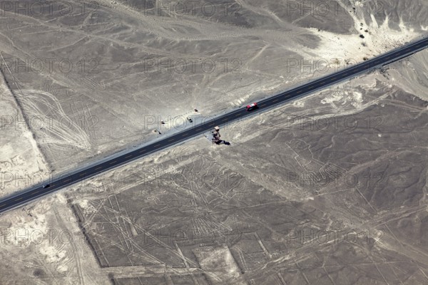 Aerial view of a dry environment with Nazca lines and a parallel road, The geoglyphs and images in