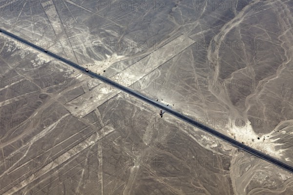 Aerial view of a road running through a desert landscape with lines, the geoglyphs and images in