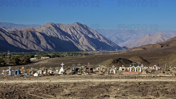 Cemetery under clear blue sky in barren desert landscape near mountains, cemetery in the Nazca