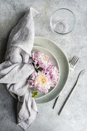 A serene table setting featuring delicate chrysanthemum flowers resting on stacked plates,