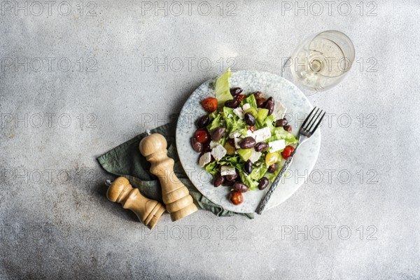 A vibrant Greek salad with tomatoes, lettuce, fermented olives, feta cheese, and olive oil