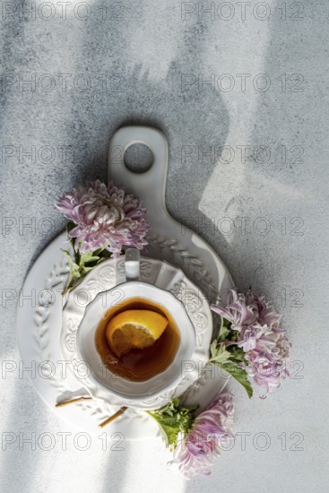 Aerial view of a rustic autumn tea setup featuring a white cup and saucer on stone, garnished with
