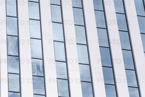 A detailed view of a modern building featuring a rhythmic pattern of white and glass vertical
