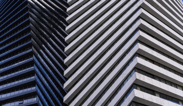 A close view of a modern skyscraper demonstrates contrasting architectural details, featuring