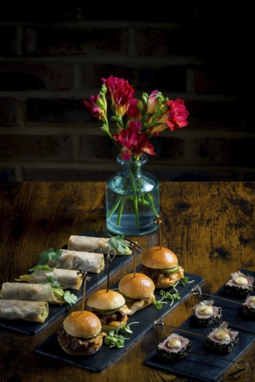 Elegant display of vegetable and courgette rolls, pulled pork and cabbage mini burgers, and rare