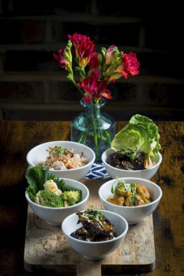 A selection of vibrant Asian cuisine bowls arranged on a wooden board The dishes feature
