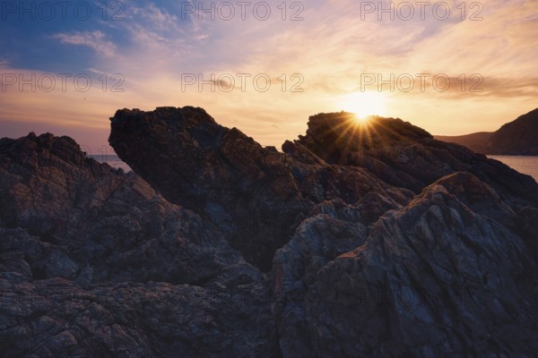 At Cala del Lastre, Portman in Murcia, Spain, a breathtaking sunset casts warm hues over rugged