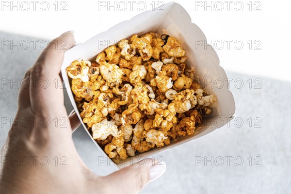 Cropped unrecognizable person in a close-up shot from above, holding a box filled with sweet