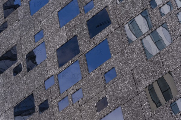 Detailed view of a modern building facade showcasing varying window sizes and a textured exterior