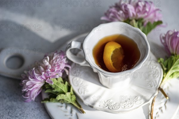 Elegant autumn-themed setup featuring a hot beverage with a lemon slice in a white cup Surrounded