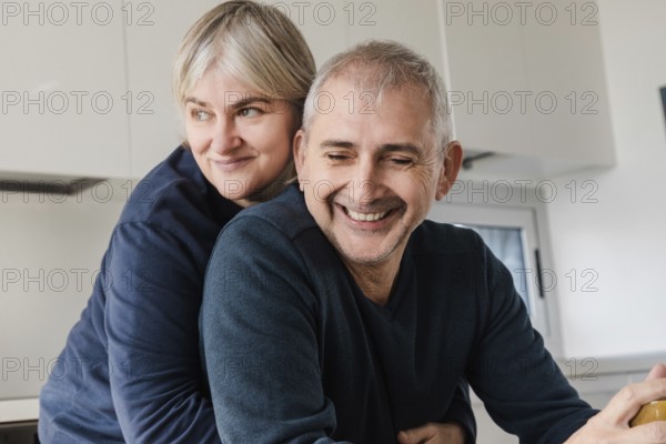 A joyful senior couple shares a tender moment, embracing in their modern kitchen The scene captures