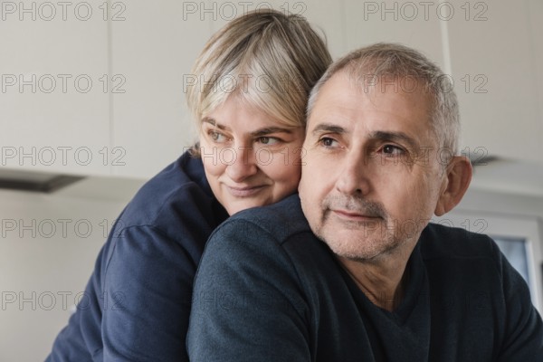 A senior couple embraces, displaying affection and warmth in a cozy home setting Their expressions