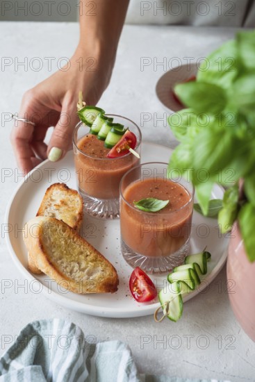 A refreshing summer meal with chilled gazpacho garnished with cucumber, tomato, and basil,