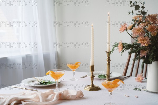 An elegantly set table featuring refreshing Mandarin drinks, lit beeswax candles, intricate floral