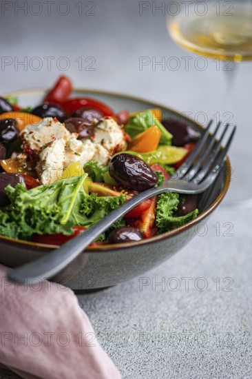 Close-up of a vibrant salad with raw kale leaves, assorted cherry tomatoes, sliced red onions, BBQ