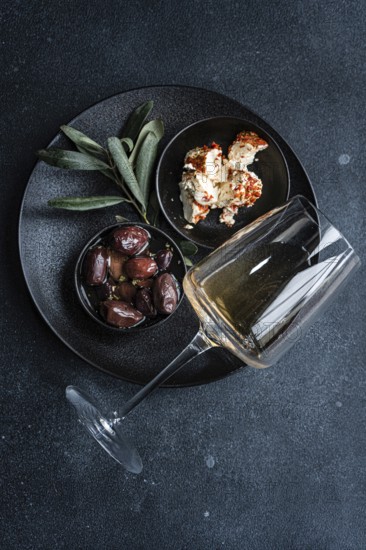 Top view of a sophisticated arrangement featuring Greek BBQ olives in a small black bowl, a portion