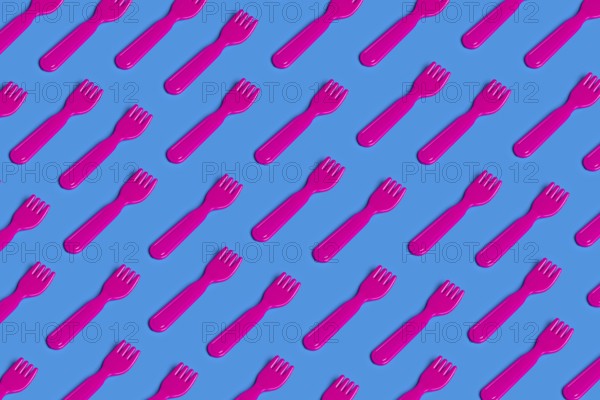 A vivid pattern of pink plastic forks on a blue background highlights the critique of junk food