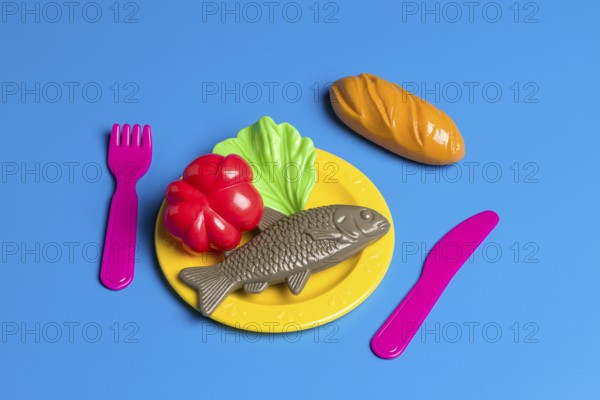 A colorful display with plastic toy food on a plate, including fish, bread, and vegetables,