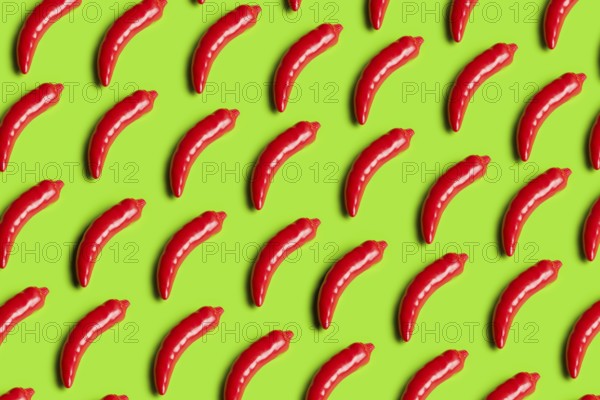 Rows of bright red plastic peppers on a bold green background This image critiques junk food