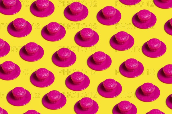 A vibrant pop art-style image featuring pink plastic cupcakes on yellow backgrounds, symbolizing